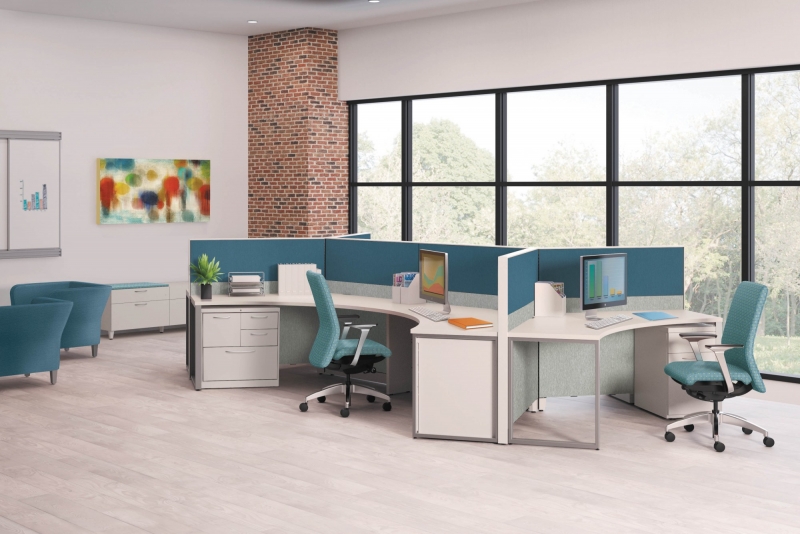 Office table pod with three teal cubicles placed together to for the pod. Each desk is curved and has a filing cabinet and a rolling teal desk chair